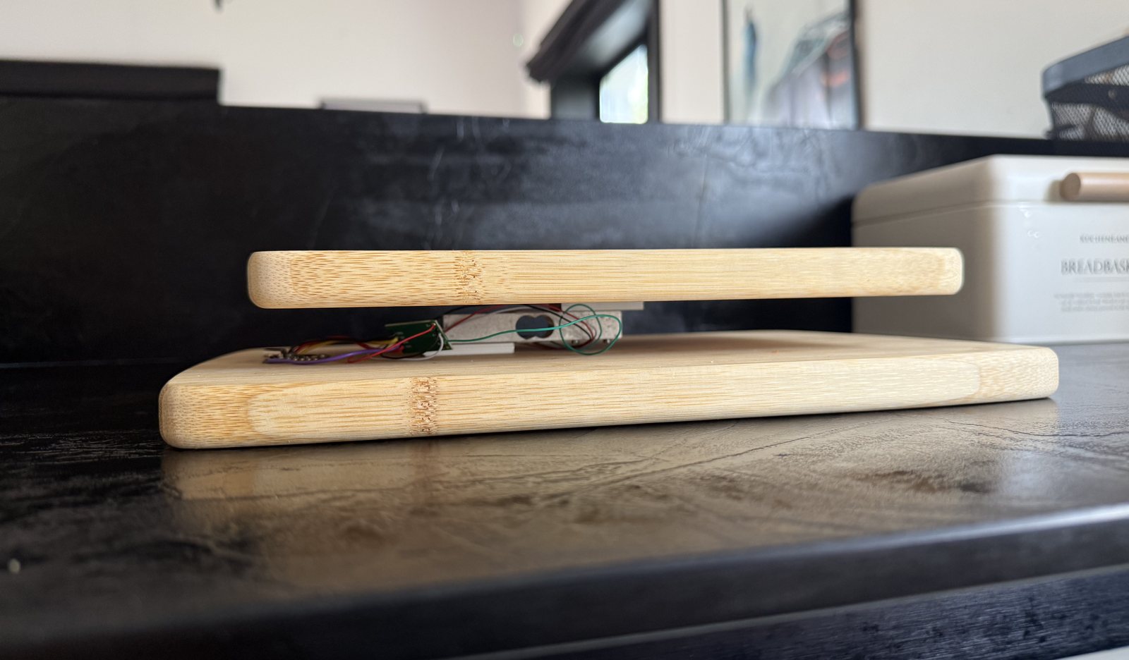 Side view of the scale: two bamboo boards with a metal load-cell beam and a green HX711 board with coloured wires visible in the gap between them
